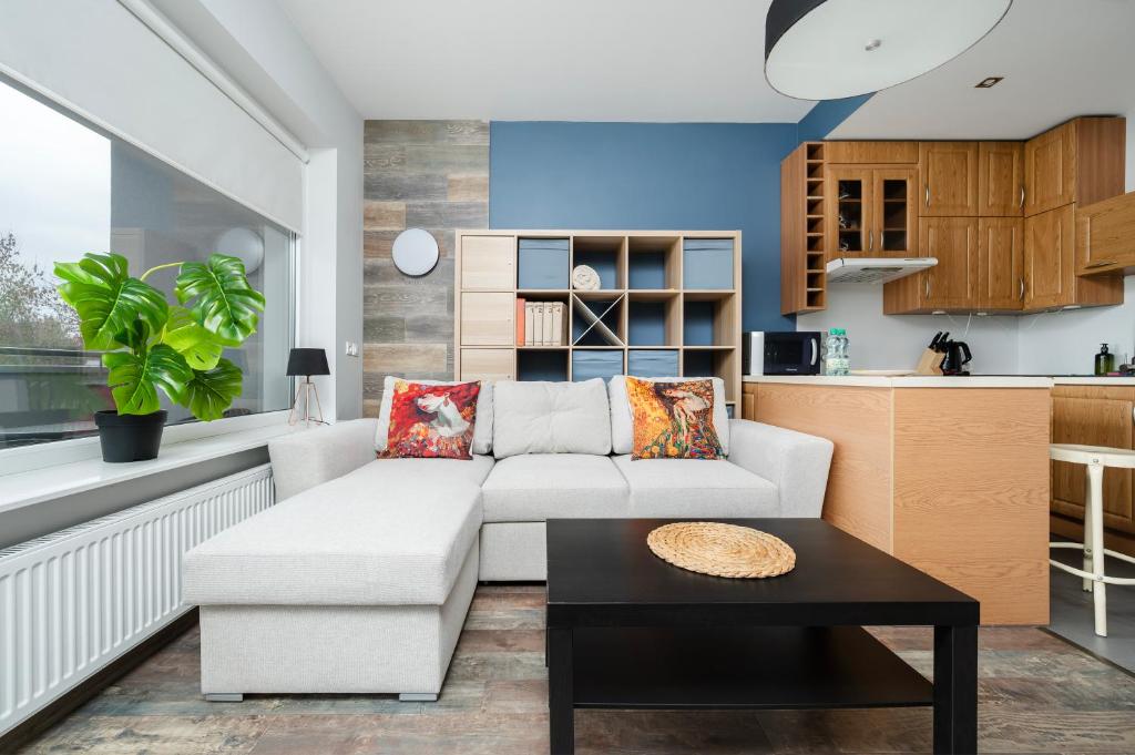 a living room with a white couch and a table at Obywatelska Comfort Apartment by BookingHost in Łódź