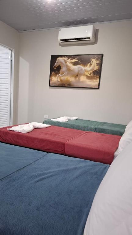 a bedroom with a bed with red and blue sheets at Suíte Harmonia 3 in Campo Grande