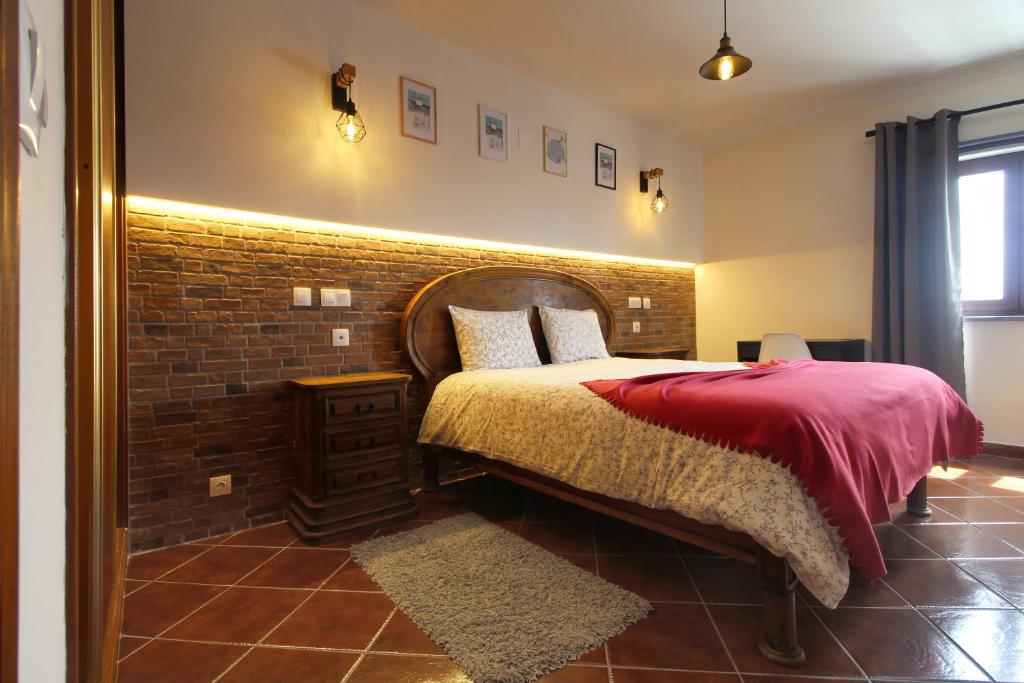 ein Schlafzimmer mit einem Bett mit einer Ziegelwand in der Unterkunft Apartamento Magnólia 80186 AL in Vila Nova de Milfontes