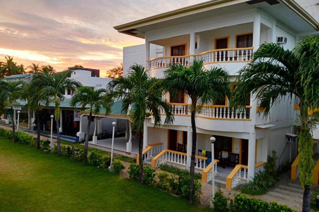 biały budynek z palmami przed nim w obiekcie Bans Beach Resort Boracay w mieście Boracay