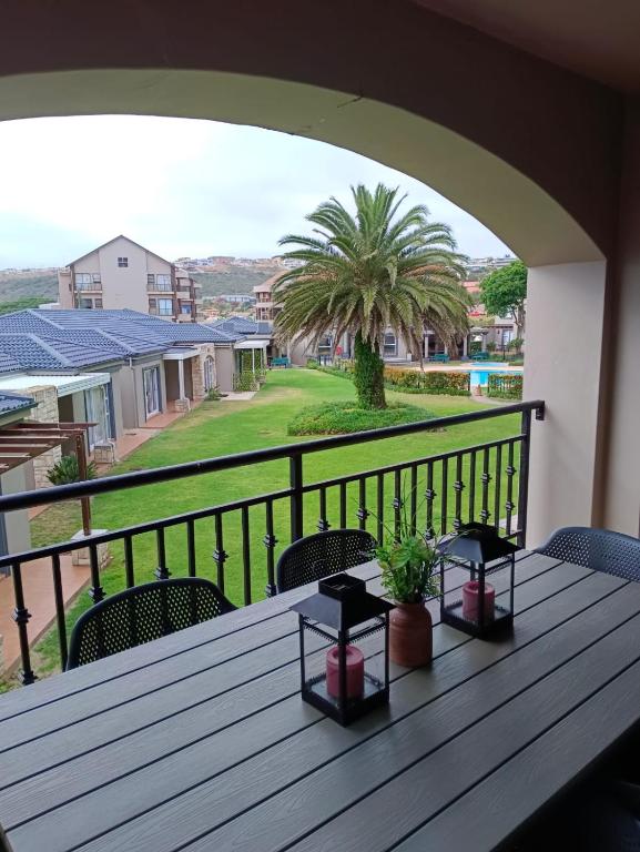 a table on a balcony with a view of a yard at Heaven at Sea in Mossel Bay
