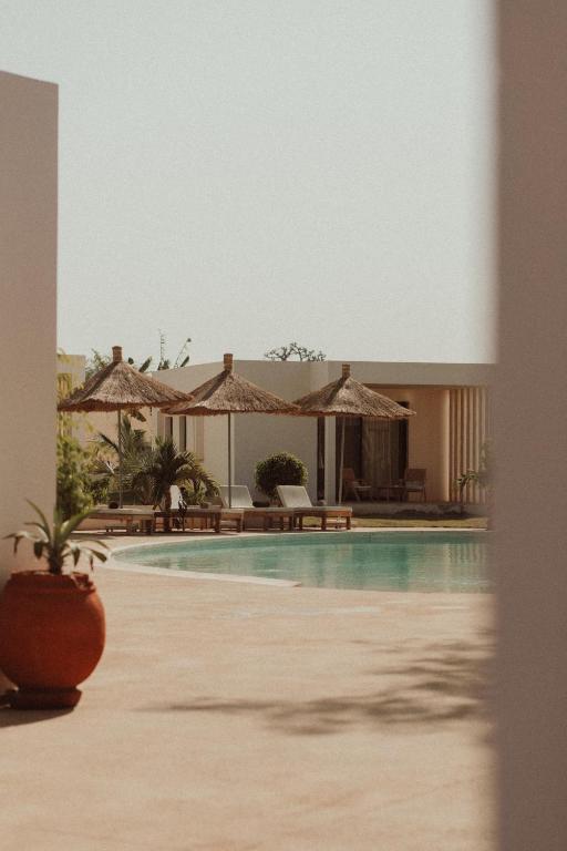 Una piscina con sombrillas y un resort. en Kawga Hôtel, en Ngaring