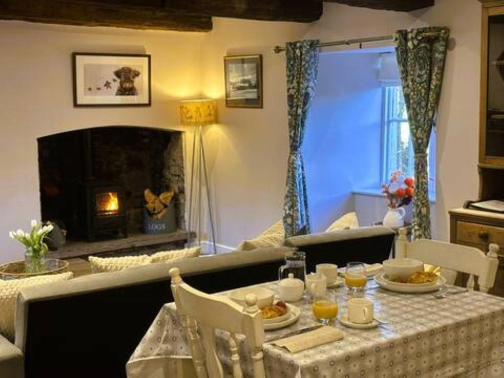 un salon avec une table et une cheminée dans l'établissement The Cottage at Sychnant Farm, à Talgarth