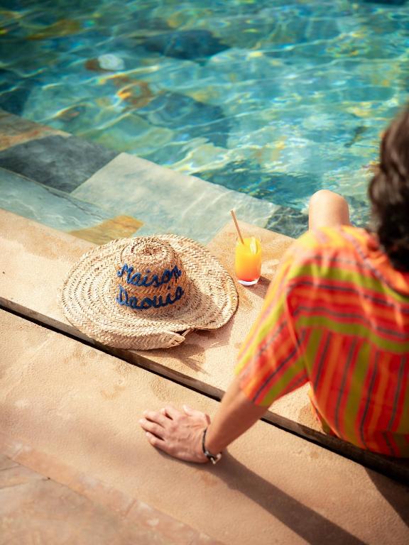 a person sitting next to a straw hat next to a swimming pool at Maison Daouia in Marrakesh
