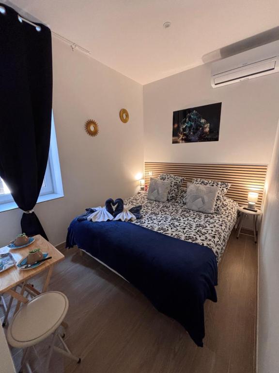 ein Schlafzimmer mit einem Bett mit einer blauen Bettdecke in der Unterkunft La Topaze in Narbonne