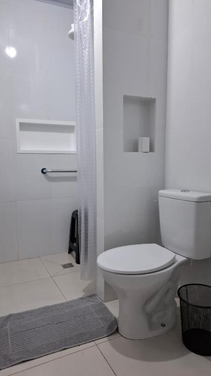 a white bathroom with a toilet and a shower at Suíte Harmonia 4 in Campo Grande