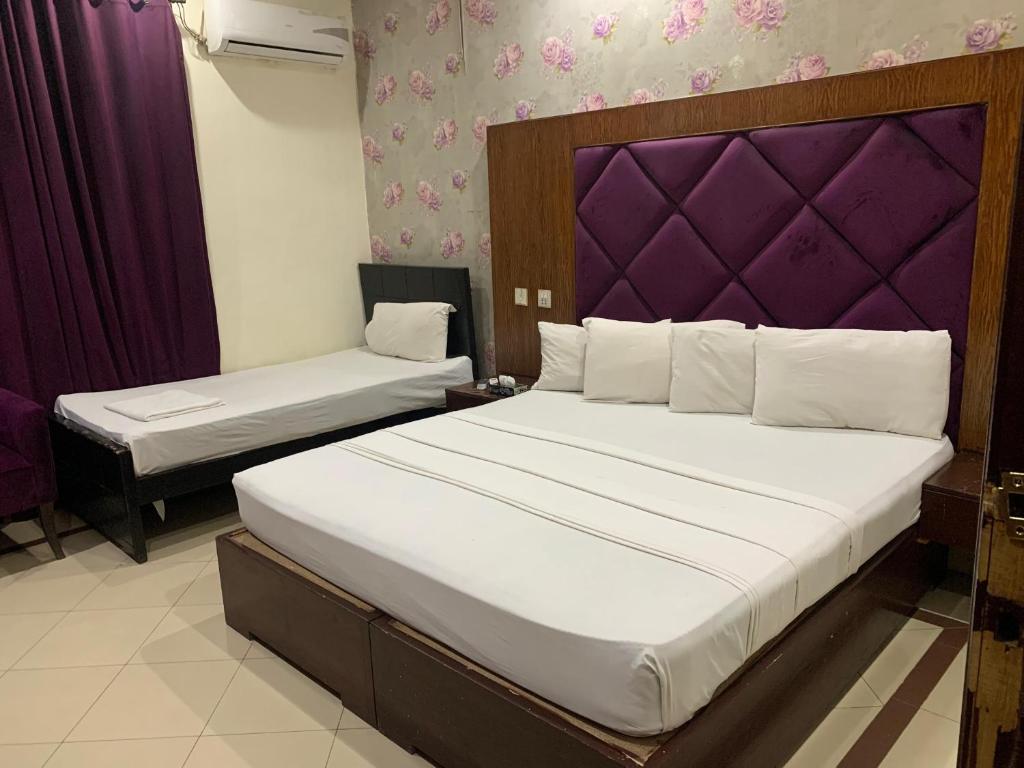 una camera con 2 letti e una testiera viola di Hotel Pak Continental Multan a Multan