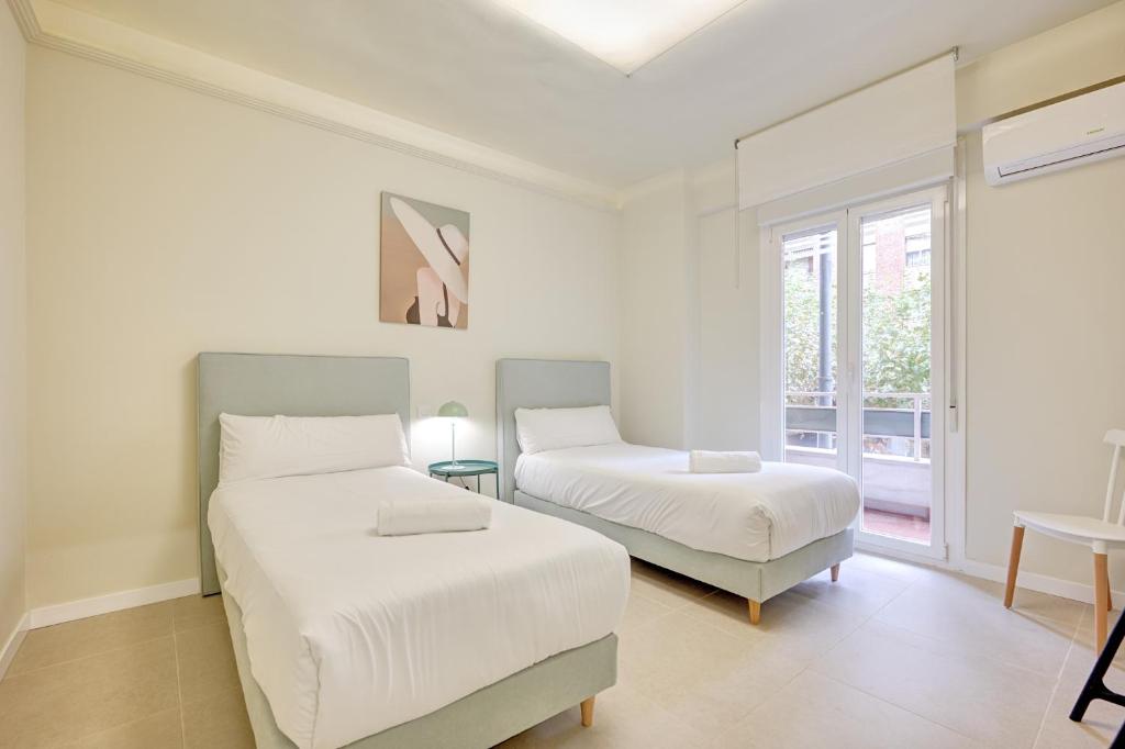 two beds in a white room with a window at Oasis by Clabao in Logroño