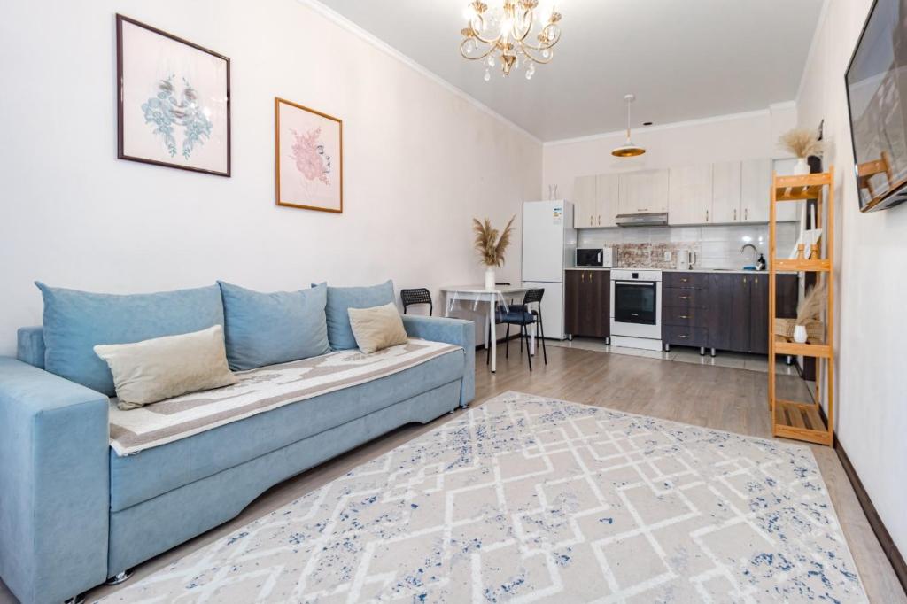 ein Wohnzimmer mit einer blauen Couch und einer Küche in der Unterkunft Апартаменты в ЖК Ирина рядом с Баянтау in Pawlodar