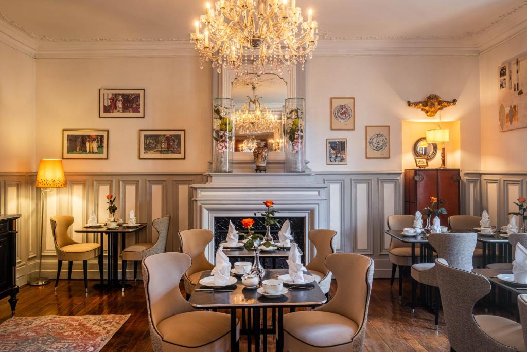 a dining room with tables and chairs and a fireplace at Le Pavillon des Lys - Hôtel Particulier in Amboise