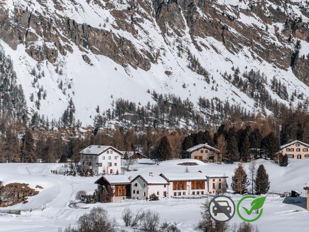 un pueblo cubierto de nieve frente a una montaña en Hotel Chesa Pool, en Sils-Maria