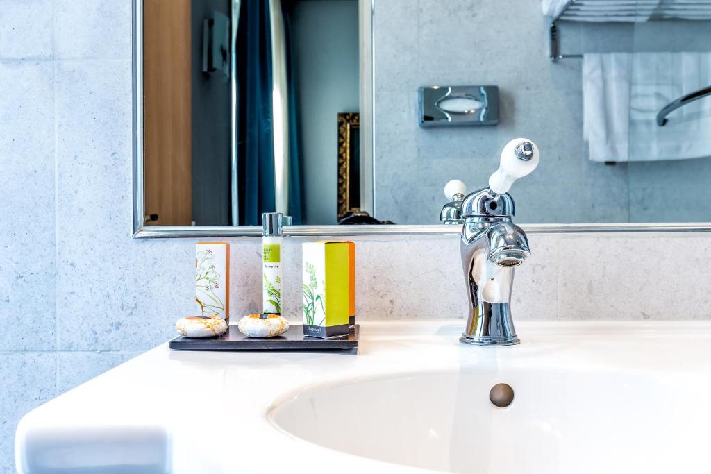 a bathroom sink with a silver faucet and a mirror at Hotel Regence Paris in Paris