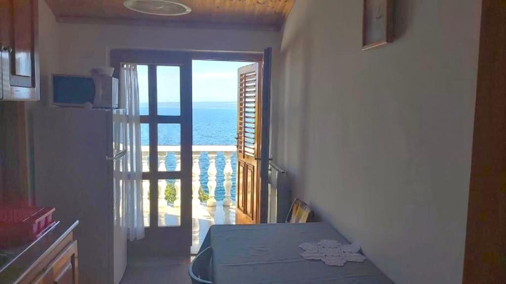 een kamer met een deur naar een balkon met uitzicht op de oceaan bij Apartment Boto in Smergo