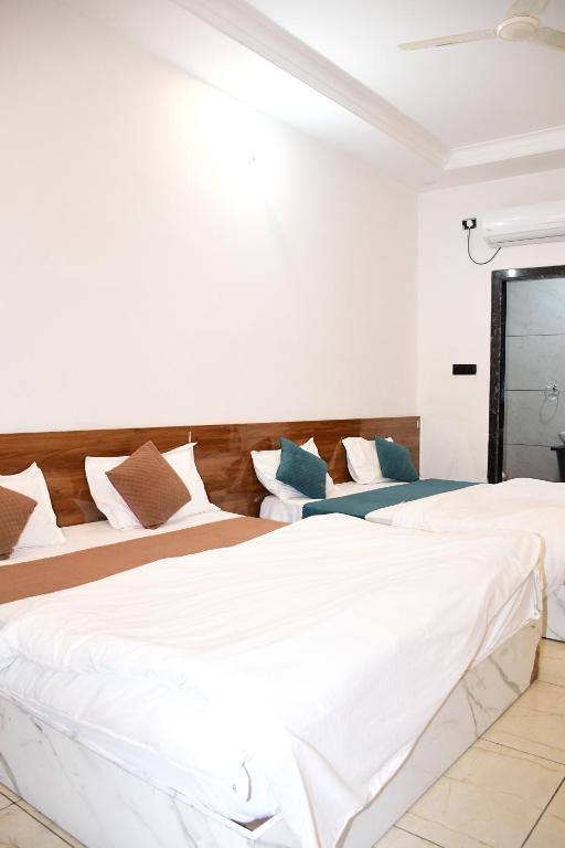 due letti in una stanza con pareti bianche di Hotel CM Palace Khatu Shyam a Khātu