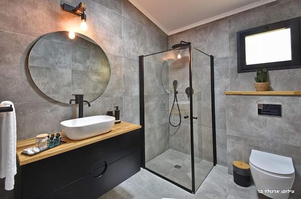 une salle de bains avec douche, lavabo et miroir dans l'établissement r בוטיק, à Manot