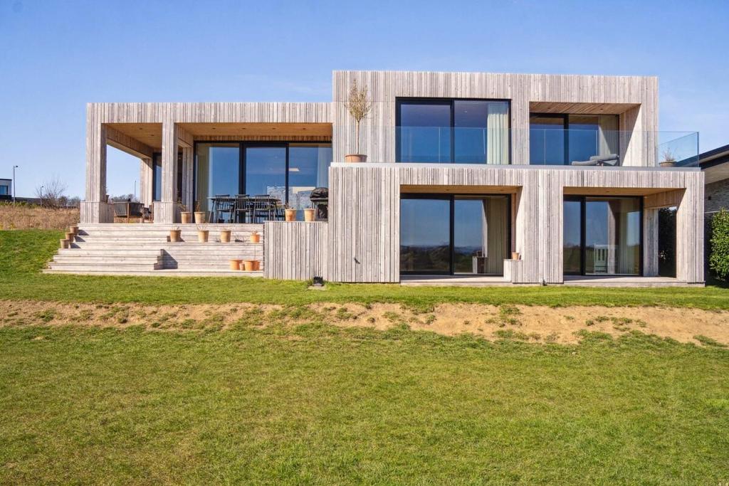 SkødstrupFantastic House by the Lake in Skødstrup Perfect for for family and long stays的草坪上设有玻璃窗户的现代房屋