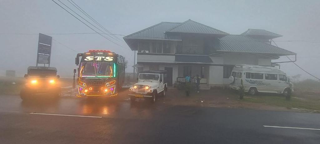 un autobus e un camion su una strada sotto la pioggia di Theeram holidays a Vagamon