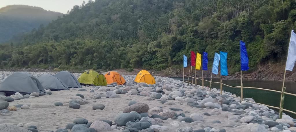 a group of tents on a river with rocks at Sunset Riverside Camping in Dawki