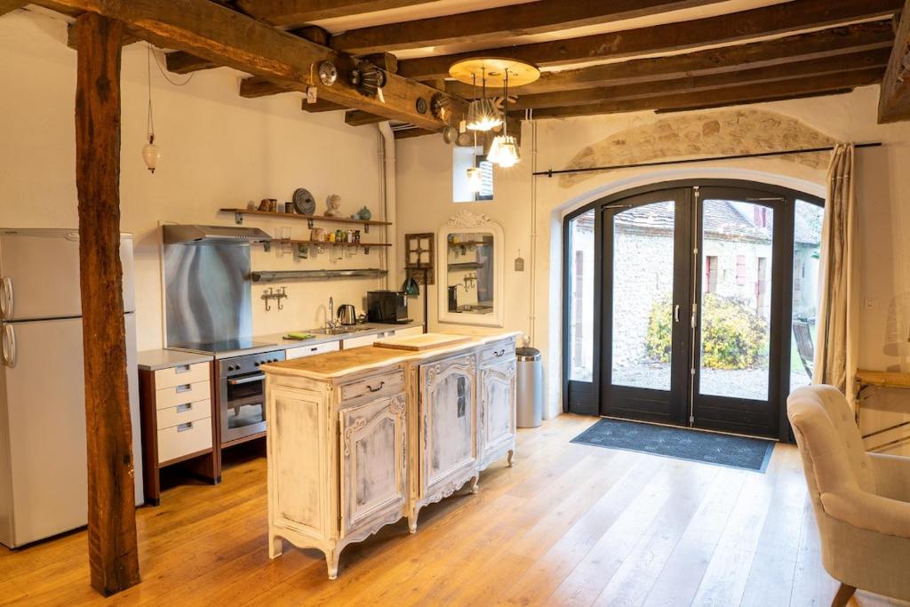 een grote keuken met houten vloeren en een groot raam bij Maison 3 in Souvigny