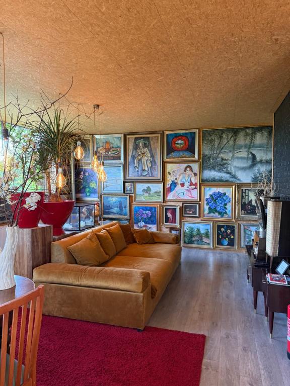 a living room with a couch and many pictures on the wall at kunstig appartement in Poelkapelle
