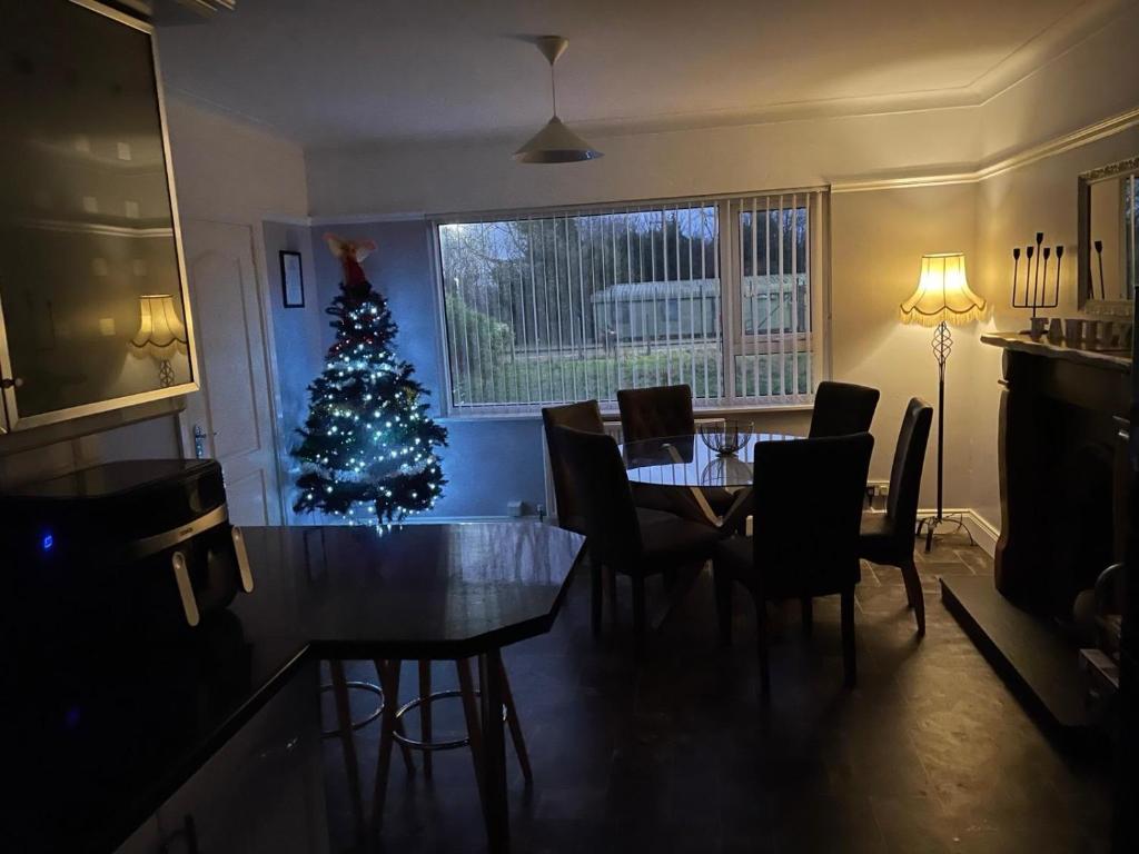 un arbre de Noël dans une salle à manger avec une table et des chaises dans l'établissement Fairway House, à Carrickfergus