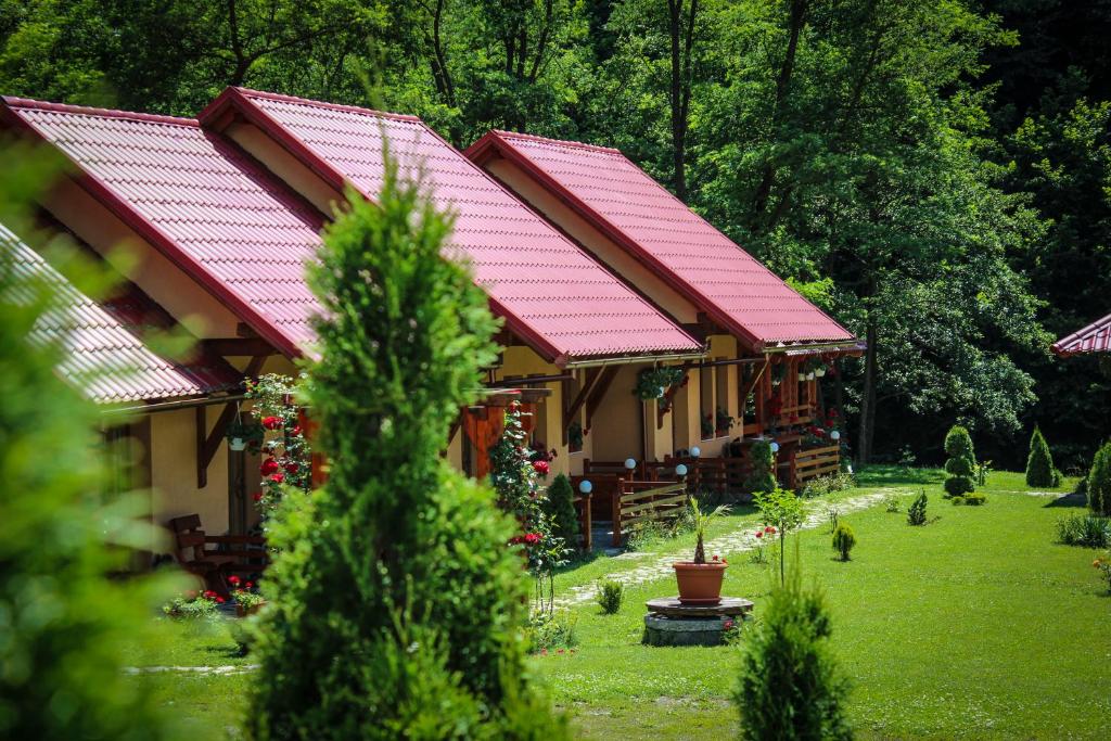 una casa con techos rojos en un patio con árboles en Patakmenti Panzió Spa, en Corund