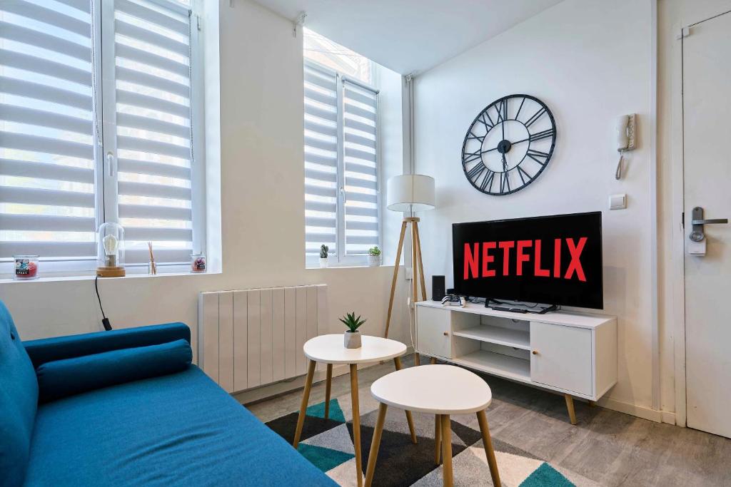 a living room with a blue couch and a clock at Le Duo - Les Demeures d'Adrien in Carvin