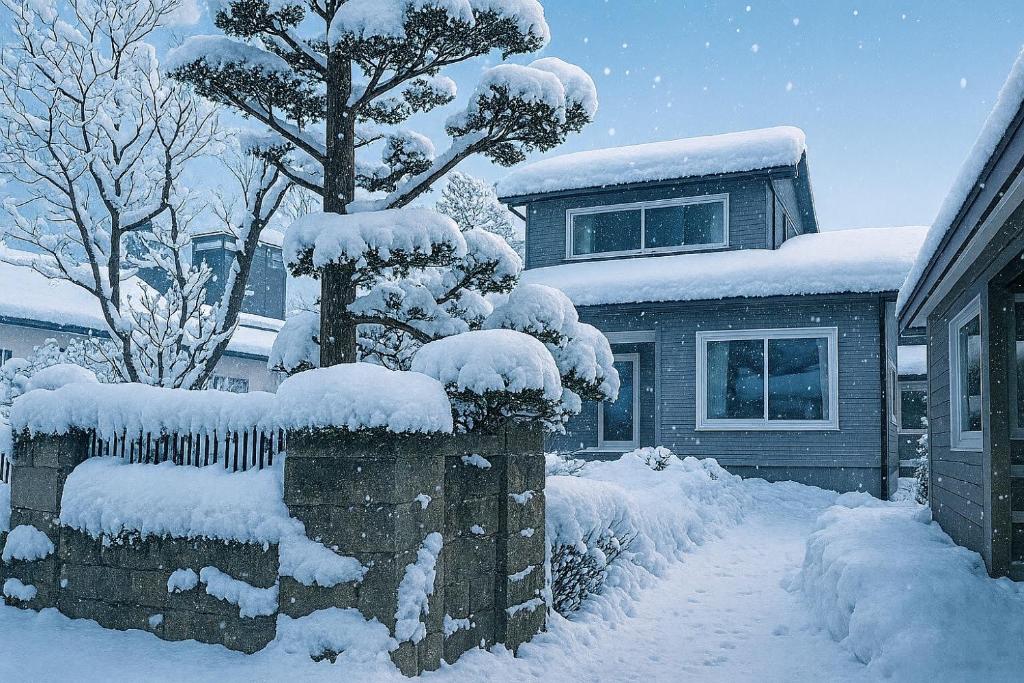 un albero innevato di fronte a una casa di 小樽-Yew Villa a Otaru