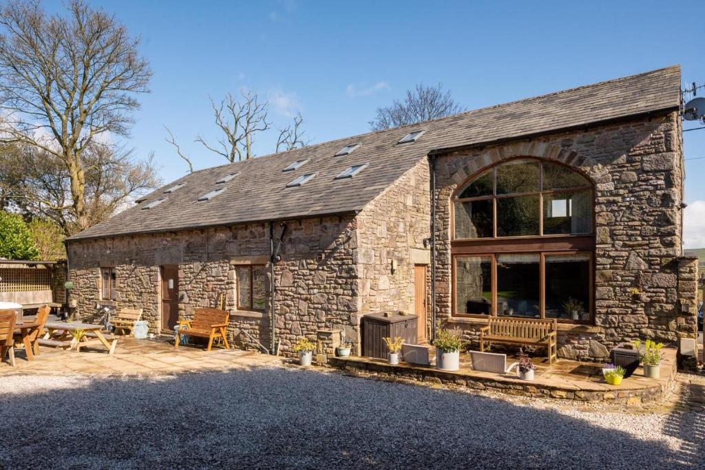 ein Steinhaus mit einem Kamin und einer Terrasse in der Unterkunft Churn Barn in Chinley