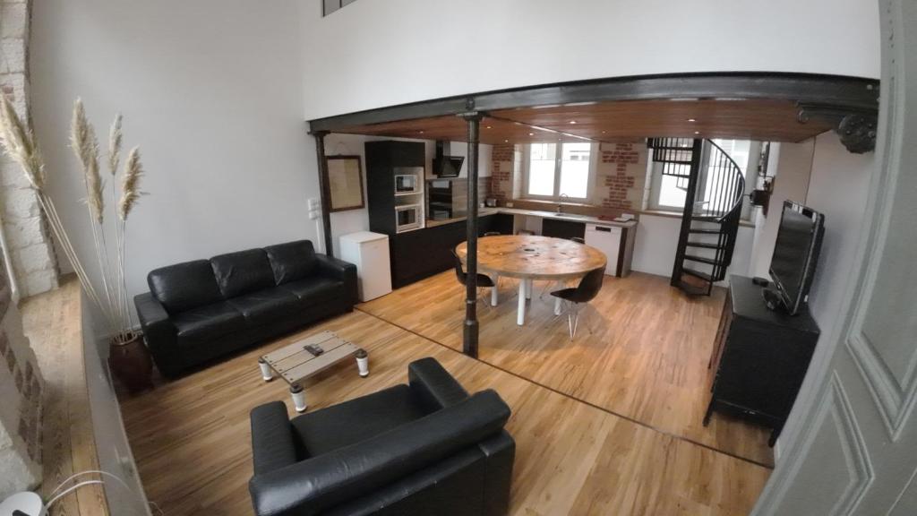 a living room with a couch and a table at Loft industriel - hyper centre cambrai in Cambrai