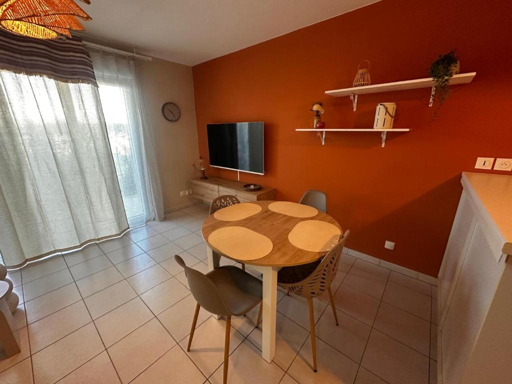 una sala da pranzo con tavolo, sedie e TV di Le Calarius - place parking gratuit a Chauray