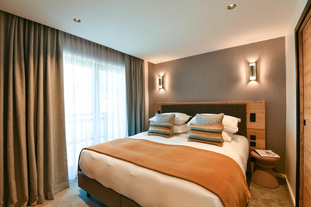 a hotel room with a large bed with pillows at Chalet Mademoiselle in Les Allues