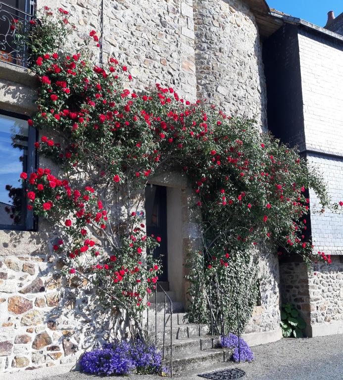 a building with red flowers on the side of it at Chambre d'hôtes dans maison de charme in La Gravelle