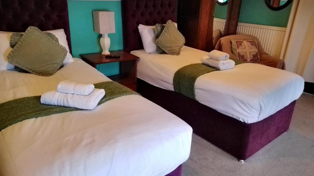 ein Hotelzimmer mit zwei Betten mit Handtüchern darauf in der Unterkunft Kings Head Hotel in Kirkbymoorside
