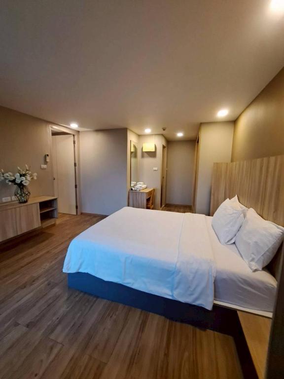 A bedroom photographed from the entrance, with a large bed and wood-look flooring.