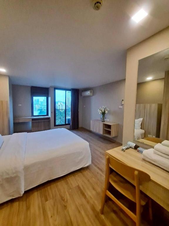 A bedroom with a large bed, window view and a compact wooden desk.
