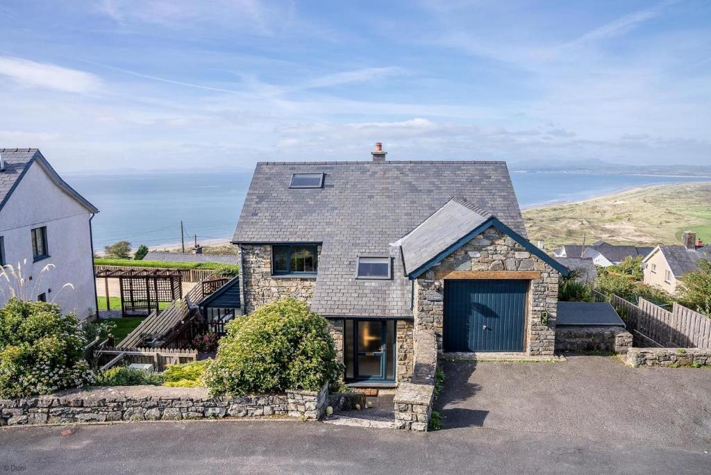 een stenen huis met garage en de oceaan bij Ty-Mari in Harlech