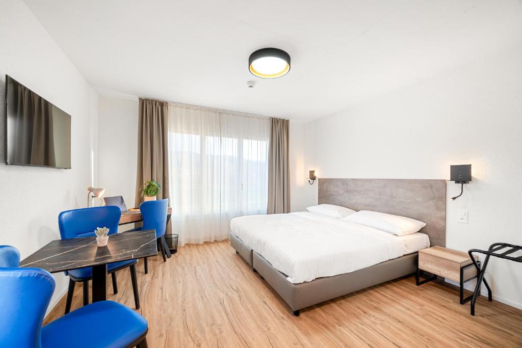 a hotel room with a bed and a table and chairs at Hine Adon Avenches A2 Hotel Aparthotel with Tea room - Self Checkin in Avenches