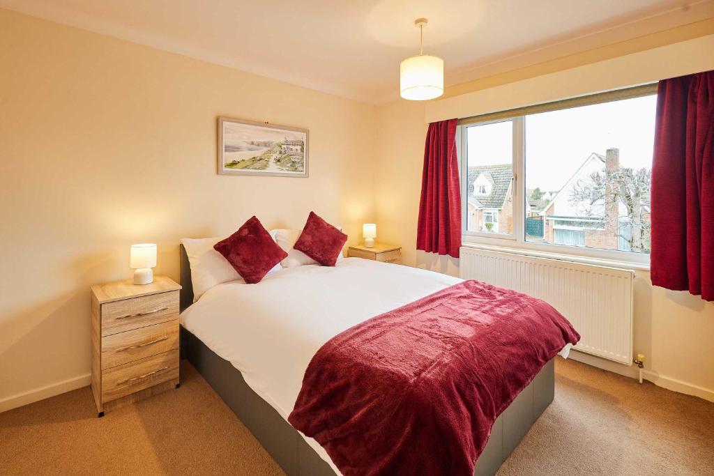 a bedroom with a bed with red curtains and a window at Host & Stay - Riders Rest in Wootton