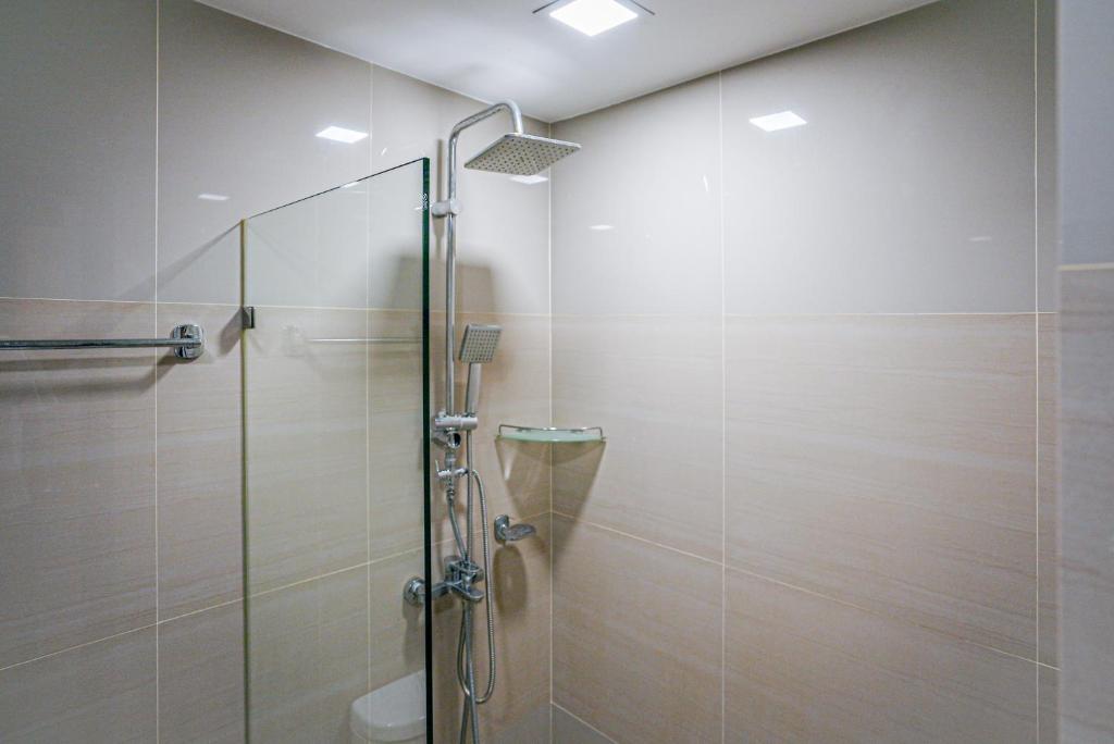 A tiled shower enclosure with a glass door and handheld shower fitting.