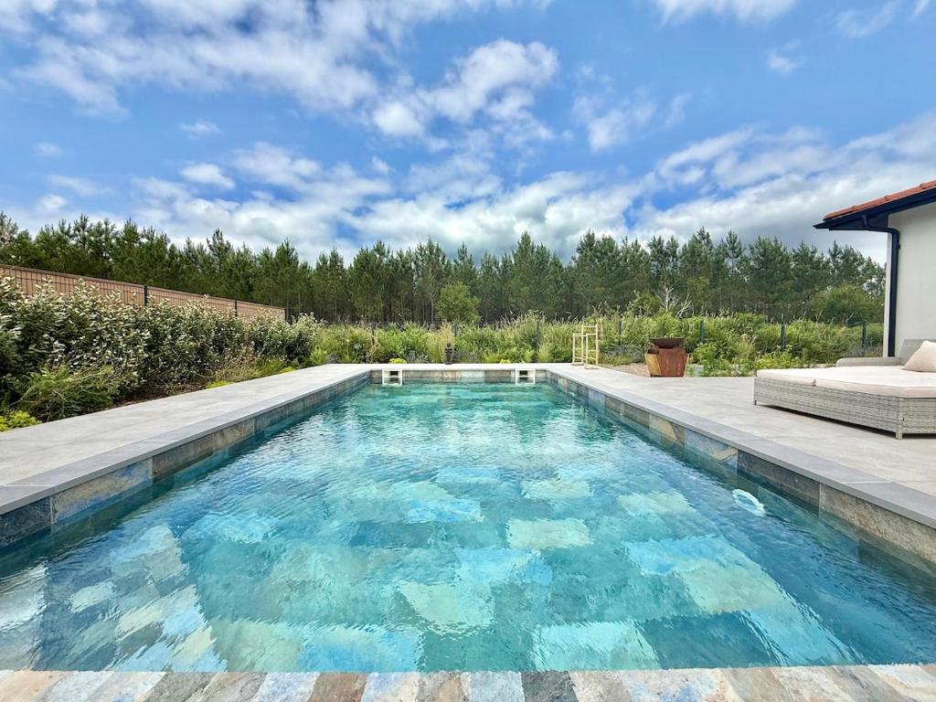 a swimming pool with blue water in a backyard at Villa Amara Piscine 7 personnes in Mios