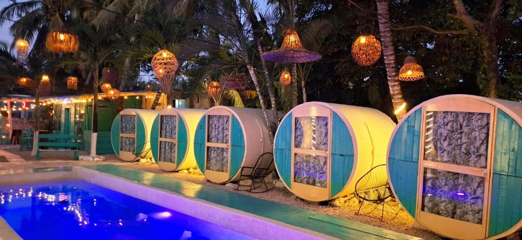 a row of domes next to a swimming pool at night at Kulu Tubohostel Bacalar in Bacalar