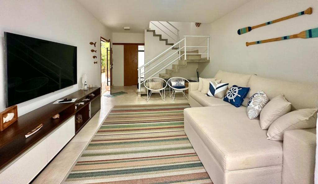 a living room with a white couch and a flat screen tv at Casa Nova em Maresias in São Sebastião