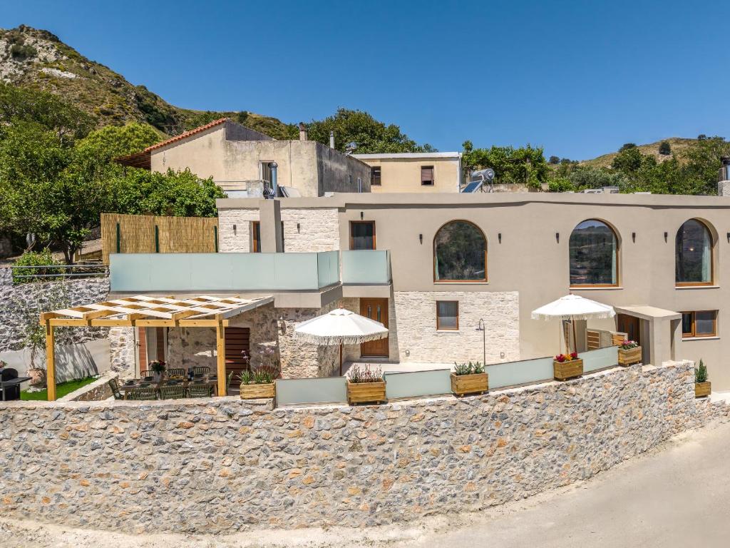 a building with umbrellas in front of it at Casa Karinea - Serene Stone House Retreat in Áyios Vasílios