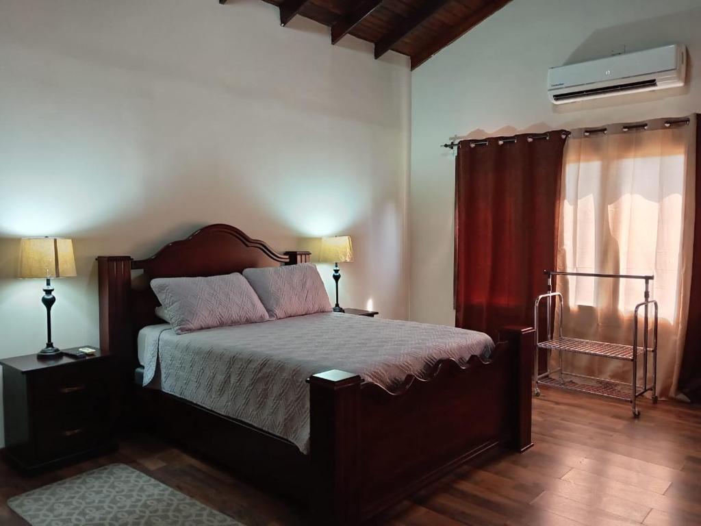 a bedroom with a bed and two lamps and a window at Villas Palmerola Comayagua in El Coquito