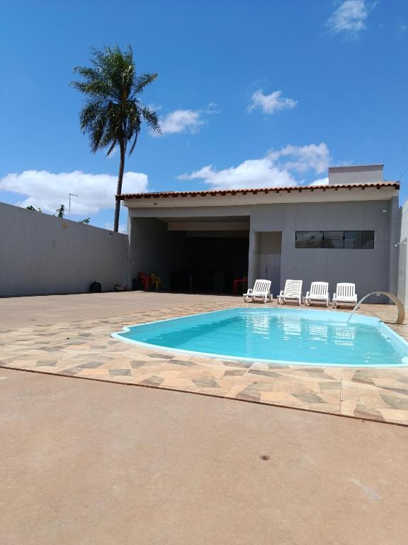 a swimming pool with two chairs and a house at Área de lazer in Assis