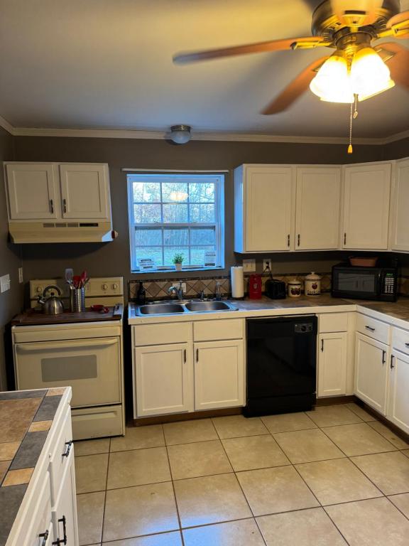 a kitchen with white cabinets and a ceiling fan at Fireflies and night skies! in French Lick