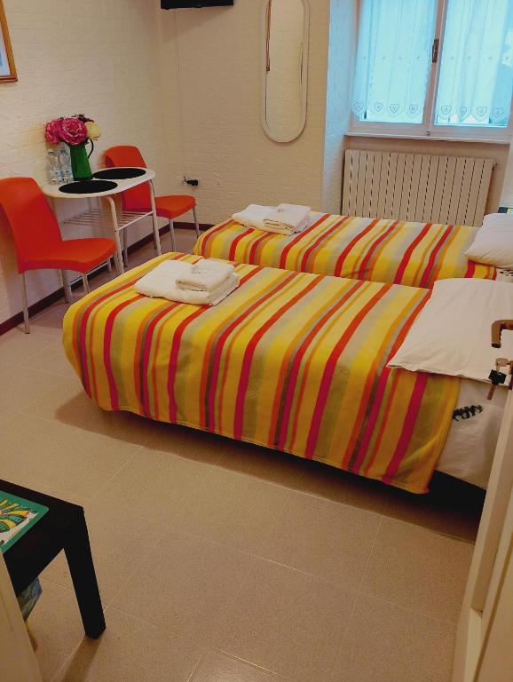 two beds in a room with a table and chairs at B&B RINGAT in Mori