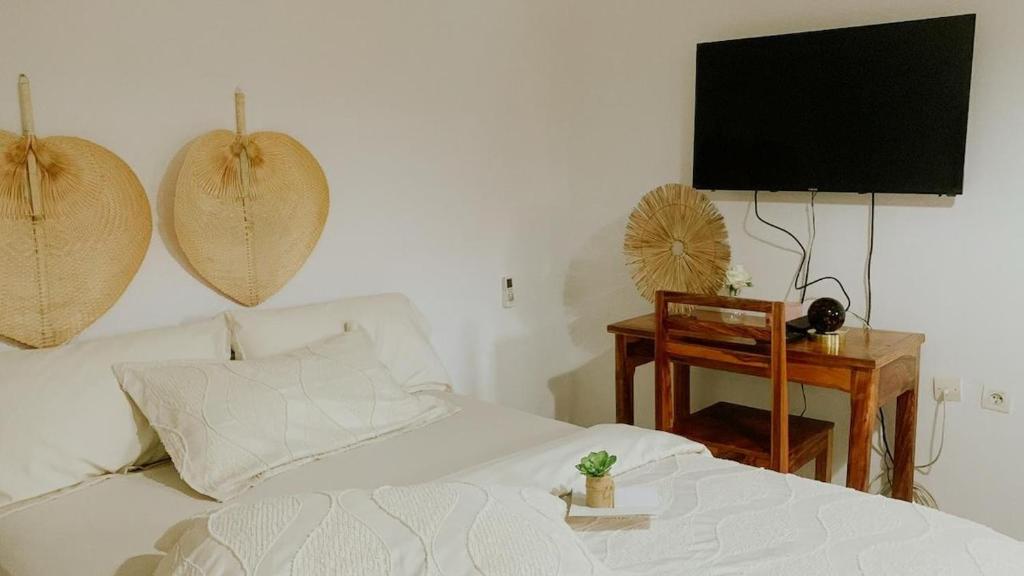 a bedroom with a white bed and a television at Suite Bohème avec Jacuzzi in Sahoué