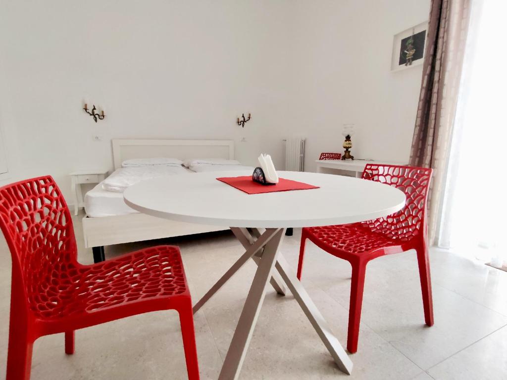 a white table with two red chairs and a bed at Tedimo Supra in Ragusa